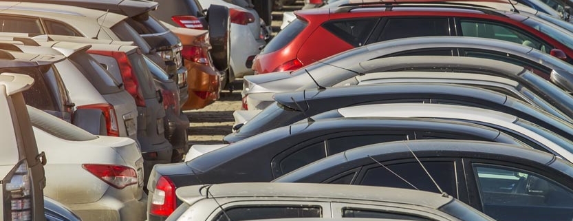 Parked used cars stand on auction parking during the day