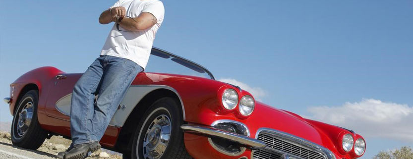 A man leaning against a red car