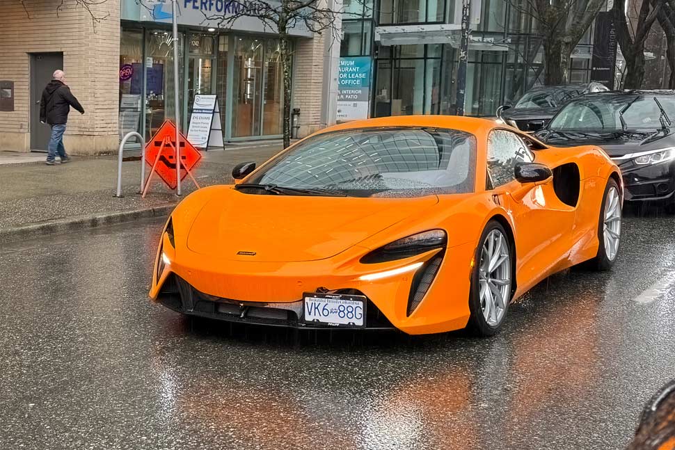 2024 Orange McLaren Artura sports car showcasing its sleek design and hybrid performance.