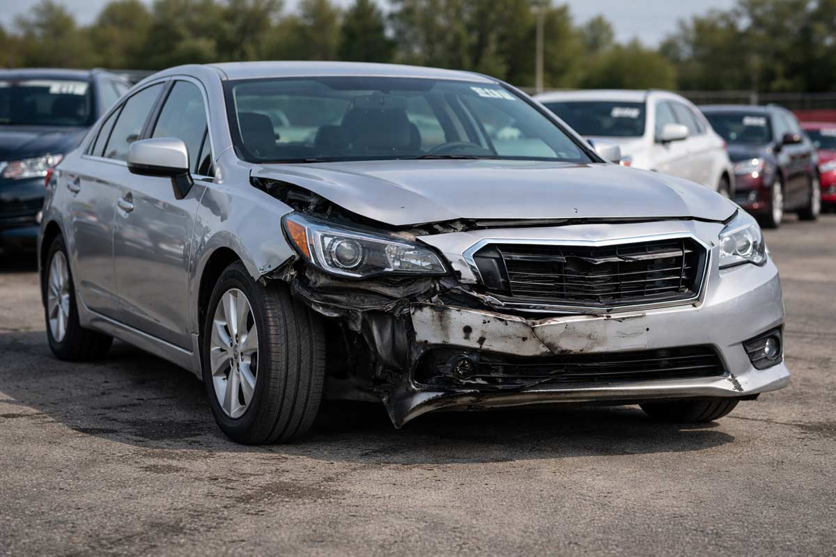 Car at auction showing frame damage indicators, including uneven wheel alignment and misaligned front end after a collision